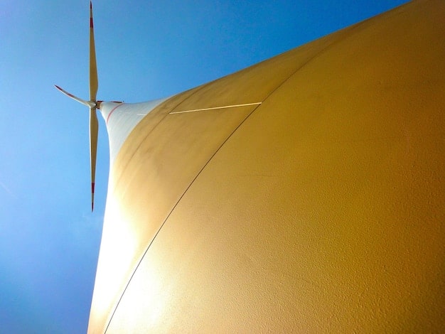 A close-up of a solar panel array with a background displaying a wind turbine farm. This image represents the diverse renewable energy sources supported by the new legislation.