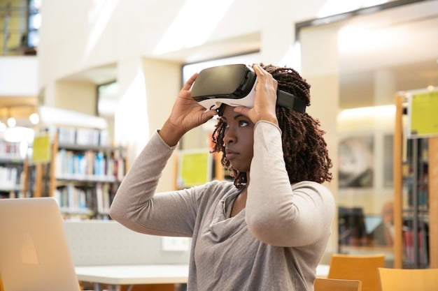 A female college student using a virtual reality headset in a computer lab, interacting with a 3D model of a complex machine, with other students working on computers and engaging in discussion in the background.