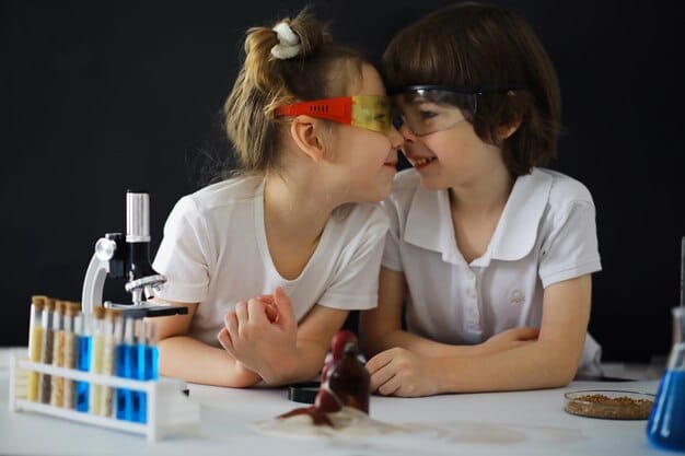 Two students, one with a visible disability, working together on a science experiment. They are both smiling and focused on the task at hand. The equipment and materials are accessible and adapted for diverse needs.